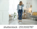 Menopause, weight gain. Concerned woman standing on floor scales at home