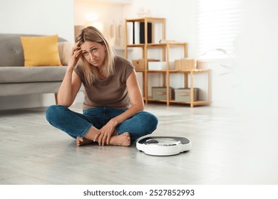 Menopause, weight gain. Concerned woman sitting near floor scales at home