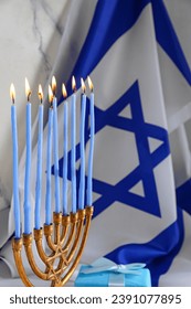Menorah with burning candles, gift and flag of Israel, closeup