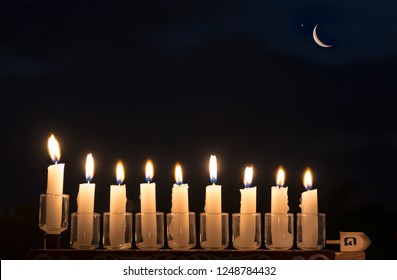 Menorah with burning candles is traditional symbol for Hebrew Holidays and celebration of Hanukkah. English translation for Hebrew letters on dreidel sides means - Great Miracle Happened There 
