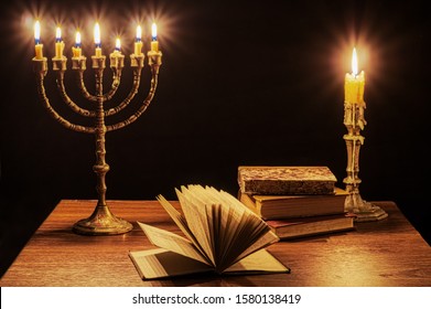 Menorah With Seven Burning Candles, Single Candlestick And Old Books.