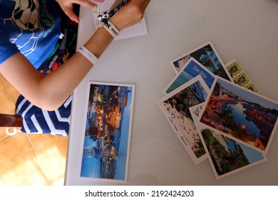 Menorca (Minorca), Spain - July 6 2022: Postcards Of The Most Famous Places Of Menorca And Postage Stamps. Child's Hand Preparing Postcards. Postcards Prepared For Sending. Holiday Postcards