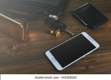 Men's Accessories (bag, Eau De Toilette, Perfumes, Car Keys, Cufflinks And Wallets With Dollars) And A Mobile Phone On A Wooden Table