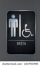 Men's Bathroom And Handicap Sign On A Wall. Braille Can Also Be Seen At The Bottom Of The Sign. Vertical Format.