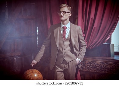 Men's beauty, fashion. Serious young blond man poses in an expensive three-piece suit, white shirt and tie in vintage interior. Luxury lifestyle.