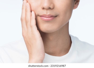 Men's beauty portrait. A young Asian man has his hand on his cheek.close up. - Powered by Shutterstock