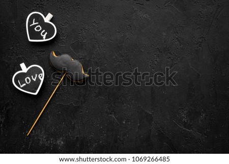 Men's birthday concept. Cookies in shape of moustache. Hearts with lettering love you on black background top view copy space