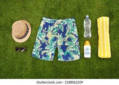 Mens Casual Summer Fashion With Accessories Items, Overhead Top View. Marketing Or Advertising Beach Or Pool Swim Clothes And Equipment For Men On Fresh Cut Grass Or Astro Turf Over Copy Space.