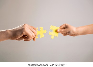 Mens and childs hands connecting puzzles. Hands connecting puzzle. Puzzles. Hand of the child and hand of mother fold puzzle, closeup. Hands hold puzzles. Solution of problems.