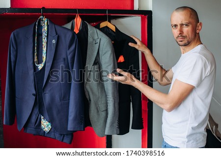 In a men's clothing showroom a guy chooses a suit for an interview