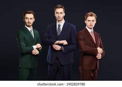 Men's Fashion. Three Handsome Men In Elegant Suits Posing Together On A Dark Blue Background. Male Beauty. Studio Portrait.