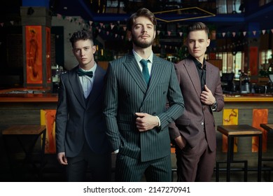 Men's Fashion. Three Handsome Men In Elegant Suits Posing Together In A Restaurant. 