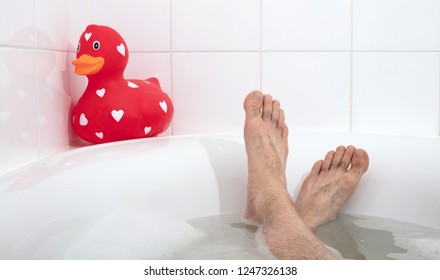 Men's Feet In A Bathtub, With Large Rubber Duck, Selective Focus