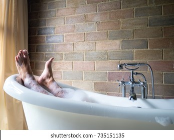 Men's  feet covered with foam bubble bath  in luxury bathtub with happiness and relaxing