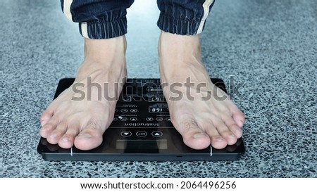 Men's feet on the scales. A pair of feet on an electronic scale to weigh on a marble background. The concept of diet and weight loss. Selective focus