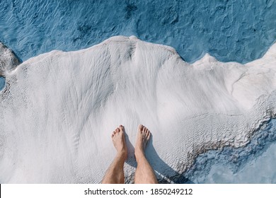 Men's feet on white calcite travertines with mineral water from thermal springs in Pamukkale, Turkey. The concept of Spa resorts and health of legs and feet