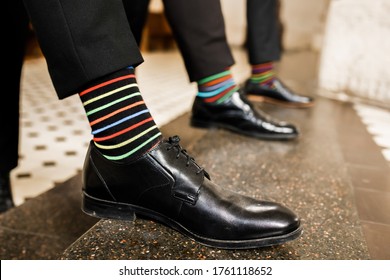 Men's feet in a row of shoes. Colored socks. Positive photo.