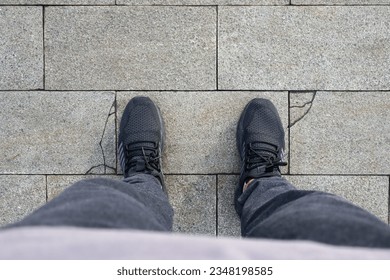 Men's feet wearing shoes stand on a paving stone road texture. Paving stones, paving background. Top view of men's feet. - Powered by Shutterstock