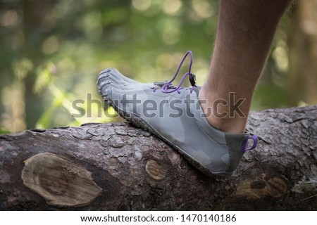 men's foot is standing on a log wearing FiveFingers shoes
