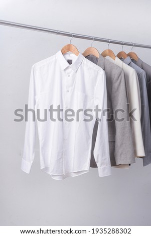 Men's four suit with long sleeved white shirt on hanger-gray background