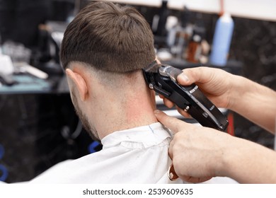 Men's haircutting with hair clipper in a barber shop or hair salon. Hairdresser service in a barbershop. - Powered by Shutterstock