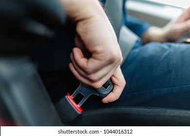 Die Männerhand hält den Sicherheitsgurt des Wagens fest. Schließen Sie den Sicherheitsgurt Ihres Autos, während Sie im Auto sitzen, bevor Sie fahren und eine sichere Reise unternehmen. Nahaufnahme eines männlichen Fahrers, der den Sicherheitsgurt anschnallt.