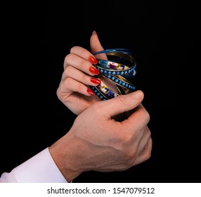 Men's hand giving blue bracelet to woman's hand on a black background - Powered by Shutterstock