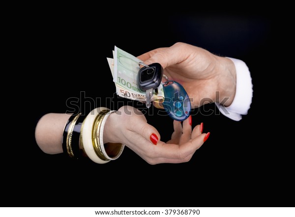 Men\'s hand giving to  woman\'s hand euro\
banknotes and car keys  in a black\
background