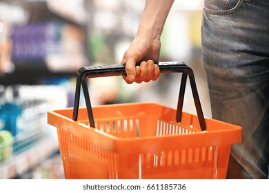 Men's Hand Holding An Empty Basket In The Supermarket. Grocery Shopping Concept.