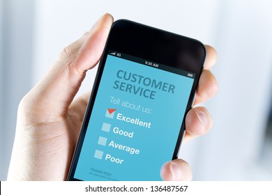 Men's Hand Holding Modern Mobile Phone With Customer Service Survey Form On A Screen. Red Tick On Excellent Choice Showing Customer Satisfaction.