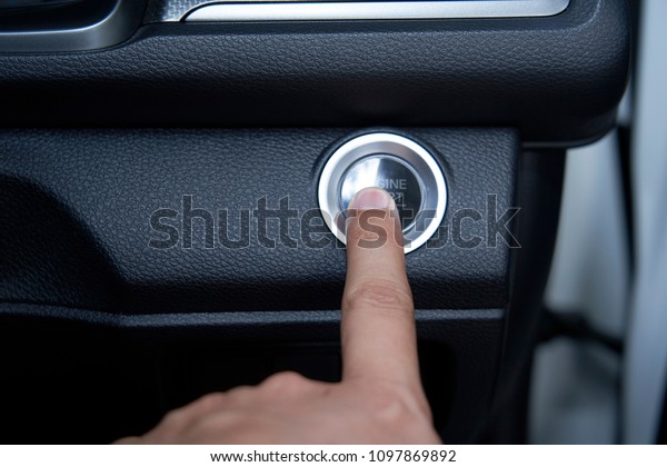 Men\'s\
hand press the engine start button. inside the\
car.