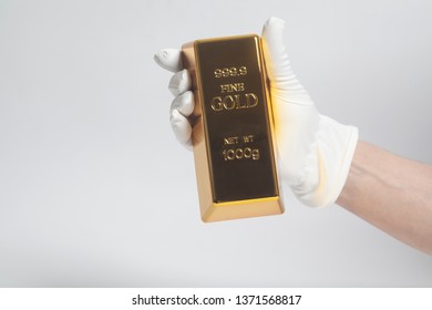 Men's Hand In White Gloves Holding A Gold Bullion