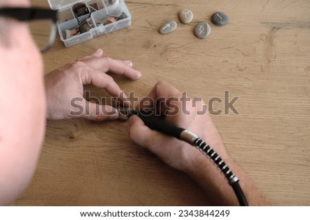 men's hands carve handmade runes