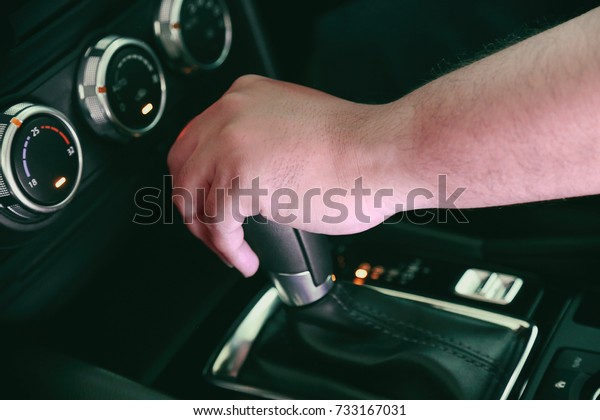 Men\'s hands are changing gear.Modern car\
driving.Focus on the background hand\
blurry.