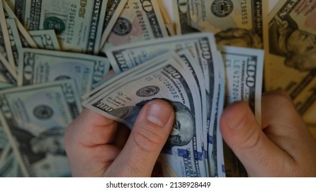 Men's hands count 1000 dollars in one hundred dollar bills against the background of money lying on the table and stretch it forward. Shifting from one hand to another, I count money and give it back