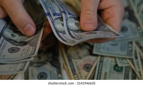 Men's hands count 1000 dollars in one hundred dollar bills against the background of money lying on the table and stretch it forward. Shifting from one hand to another, I count money and give it back