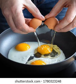 Men's Hands Cracking Eggs Into Hot Iron, Cooking Fried Eggs