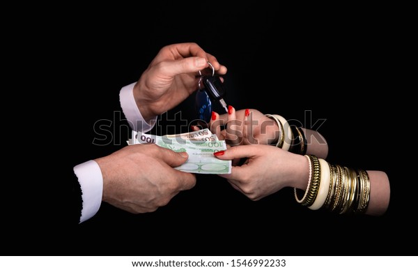 Men\'s hands giving to  woman\'s hands\
euro banknotes and car keys  in a black\
background