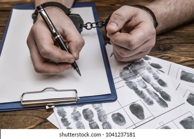 Men's Hands With Handcuffs Fill The Police Record, Confession. On Top Of The Police Investigative Detective. Arrest, Bail, Criminal, Prison. Fingerprints, Criminalist. The Attacker. Close-up