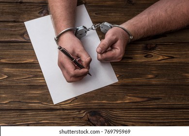 Men's Hands With Handcuffs Fill The Police Record, Confession. On Top See The Police Investigative Detective. Arrest, Bail, Criminal, Prison.