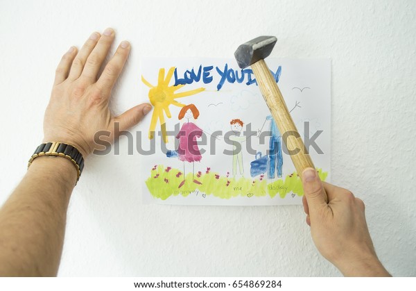 Men\'s hands hang\
a child\'s picture on the\
wall