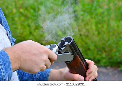 Men's Hands Hold A Hunting Rifle, Smoke Comes From The Muzzle After The Shot