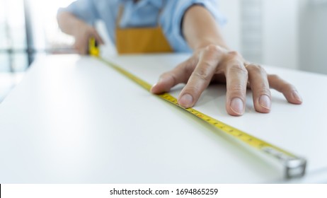 Men's hands hold a measuring tape measuring with flexible ruler for home renovation. repair, architecture and home renovation building and home concept - Shutterstock ID 1694865259