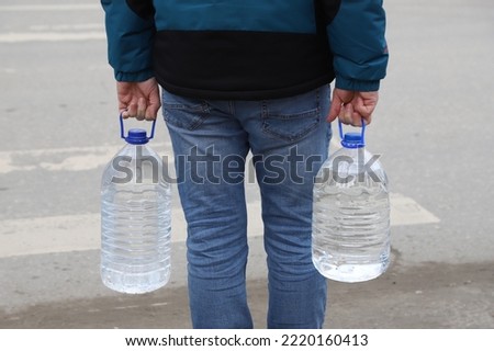 men's hands hold two plastic five-liter water bottles