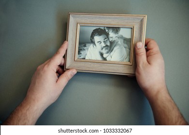 Men's hands hold a wooden frame with a black and white photo. Sentimentality on father's day. - Powered by Shutterstock