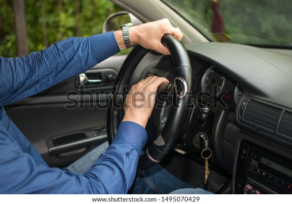 \
men\'s hands on the wheel of\
a car