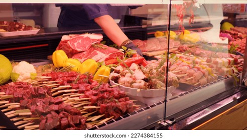 Mens hands picking chicken barbecue on skewers to be weighted. Window shop with different meat goods in butchers store. - Powered by Shutterstock