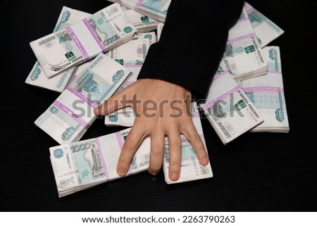 men's hands reach for a wad of money. A million rubles on the black table. The concept of wealth, success, greed and corruption, lust for money