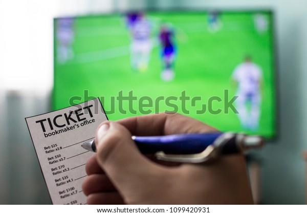 Men\'s hands\
with a ticket bookmaker\'s office, on TV show football, Champions\
League, sports betting,\
close-ups