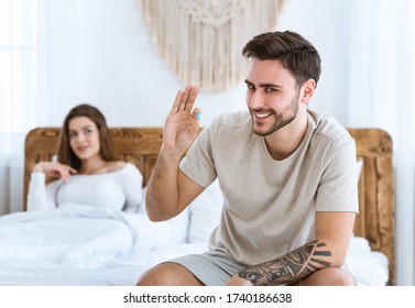 Mens health and libido concept. Smiling man takes viagra before sex, woman looks at him and smiles in bed.